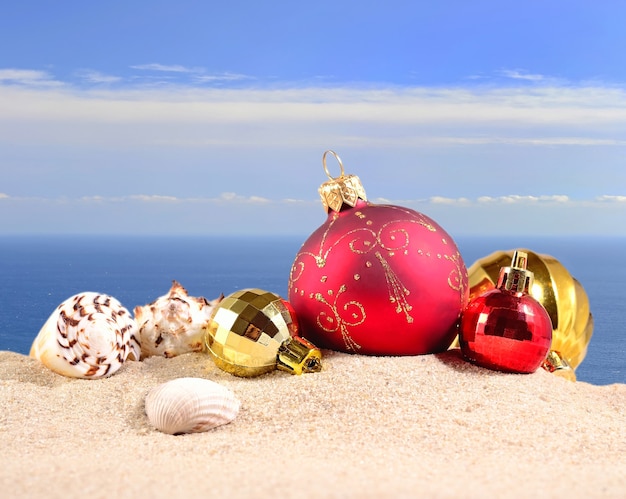 Decorações de Natal e conchas na areia da praia contra o fundo do mar