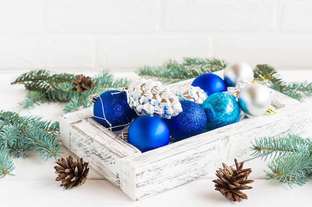 Decorações de Natal em uma caixa de madeira sobre uma mesa branca com ramos de abeto e cones. o conceito de ano novo e Natal.