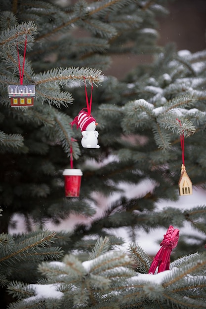 Decorações de natal na árvore com neve ao ar livre