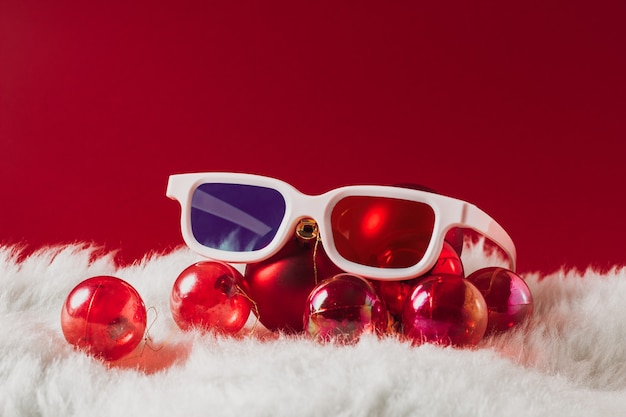 Decorações de natal, óculos para cinema 3d em um fundo vermelho. conceito de filmes de ano novo