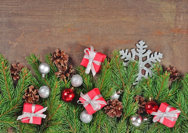 Decorações de Natal prateadas e vermelhas e galho de abeto e cones em um fundo de madeira