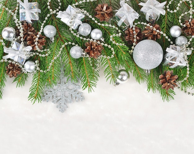 Decorações de Natal prateadas em um galho de abeto em um fundo branco