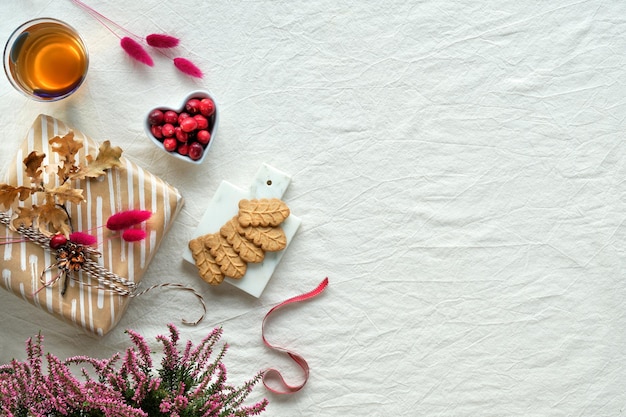 Decorações de outono, biscoitos de cranberry, chá e folhas secas de carvalho de tecido branco plano com