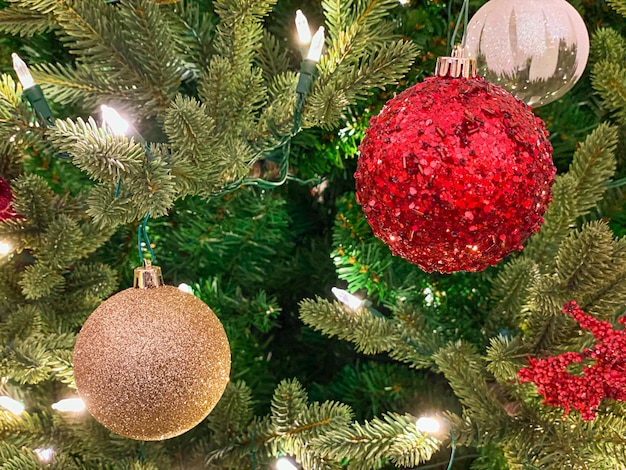 Decorações vermelhas e douradas na árvore de Natal Bolas de Natal no galho de árvore Fundo de Natal