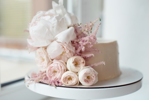 Foto decorado con flores frescas, pastel blanco desnudo, un pastel elegante