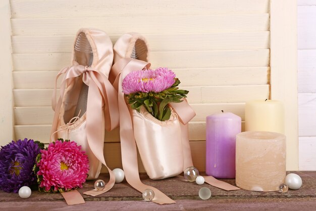 Decorado con flores y velas, zapatillas de ballet sobre mesa de madera color crema