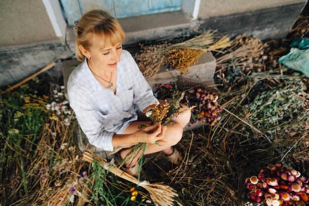 El decorador se sienta en un ramo de flores secas y hace una composición con cara seria