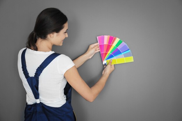 Decoradora feminina segurando amostras de paleta de cores contra o cinza