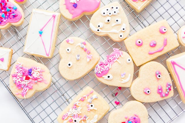 Decorando biscoitos de açúcar em forma de coração com glacê real e granulado rosa para o dia dos namorados.