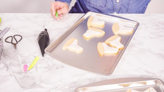 Decorando biscoitos de açúcar em forma de patins de gelo com glacê real de cor branca.