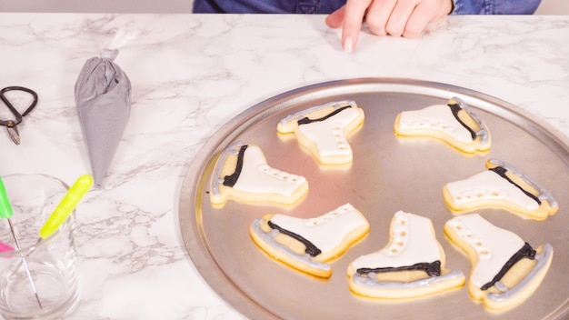 Decorando biscoitos de açúcar em forma de patins de gelo com glacê real de cor preta.