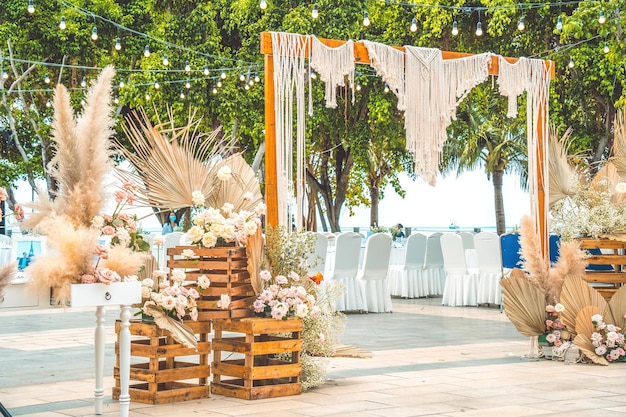 Decorando o arco com flores e tecido para uma cerimônia de casamento na natureza Cerimônia de casamento com flores no jardim com luzes penduradas
