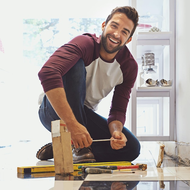 Decorando um ladrilho de cada vez Retrato de um homem sorridente colocando ladrilhos