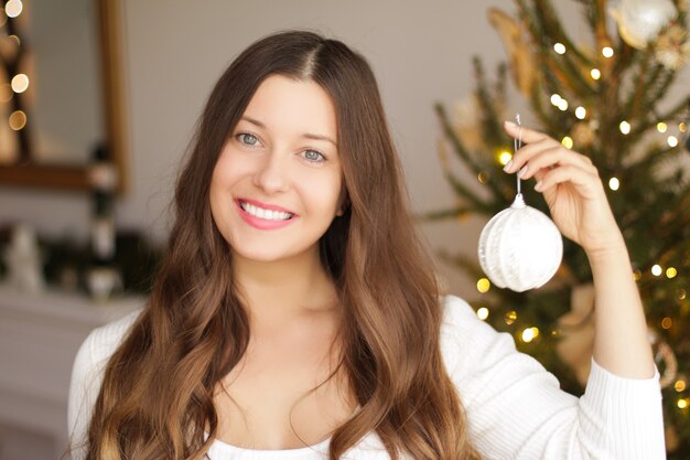 Decorar a árvore de natal e o conceito de férias de inverno mulher sorridente feliz segurando o ornamento festivo ...