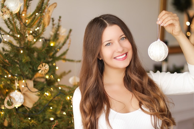 Decorar a árvore de natal e o conceito de férias de inverno mulher sorridente feliz segurando o ornamento festivo ...