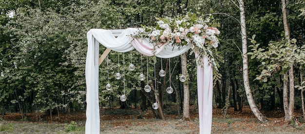 Decorar el arco con flores y telas para una ceremonia de boda en la naturaleza