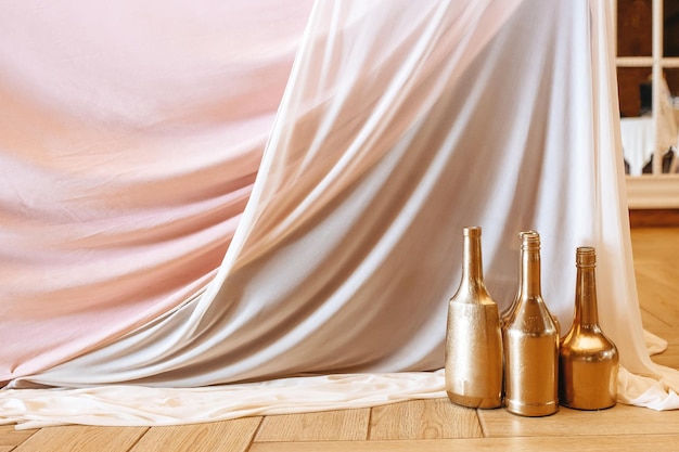 Decorar la mesa con jarrones de botellas doradas y tela para un banquete de boda