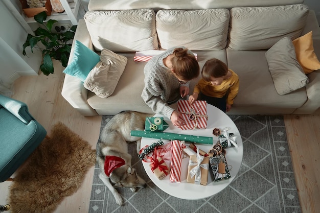Decorar regalos de Navidad familia madre hijo y mascota perro envolver caja de regalo de Navidad juntos vista superior