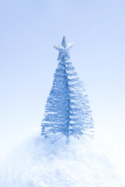 Decorativa pequena árvore de Natal prateada em fundo de neve fofa.