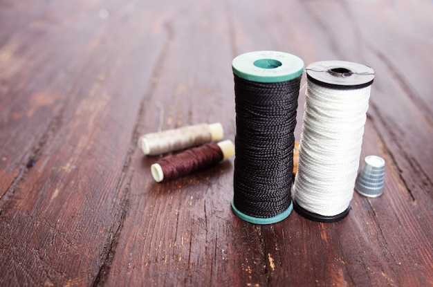 Dedal y agujas para coser de cerca sobre un fondo de madera