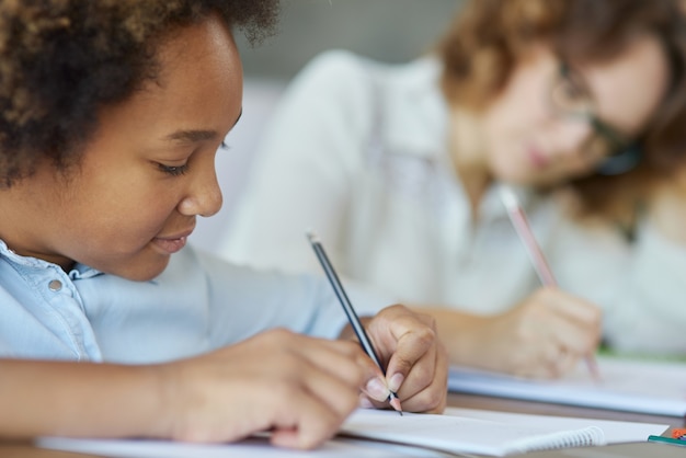 Foto dedicação, close-up, foto de menina adolescente mestiça parecendo concentrada enquanto escrevia com lápis