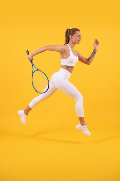 Dedicado al fitness. entrenamiento de jugadores de tenis o bádminton. estilo de vida saludable y activo. éxito deportivo. mujer salta con raqueta. chica enérgica con raqueta de tenis. la dama corre hacia el éxito.