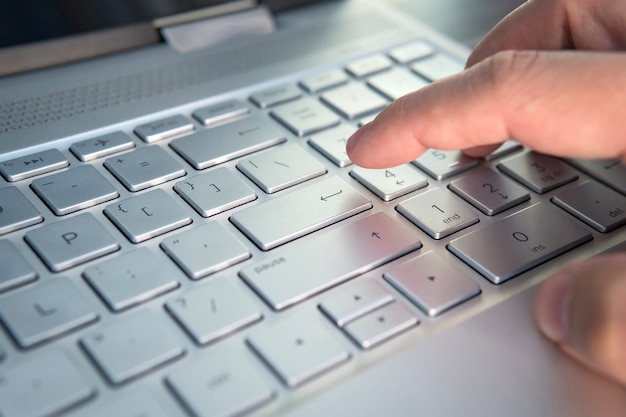 Dedo apertando o botão do teclado. clique na tecla cinza do ultrabook