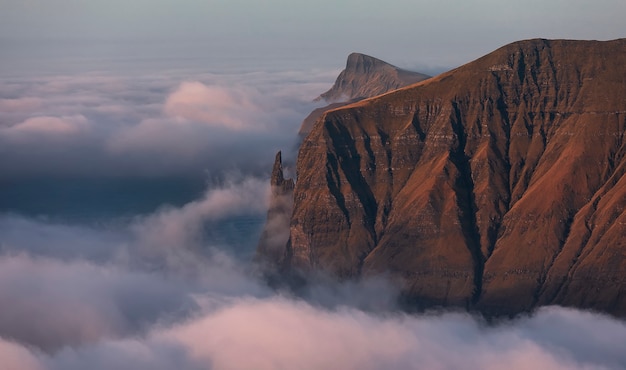 Dedo da bruxa do rock ao amanhecer. nuvens cobriam o oceano atlântico. ilhas faroé, europa.