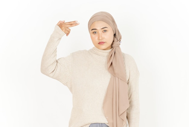 Dedo de arma na cabeça de uma linda mulher asiática usando um hijab isolado no fundo branco