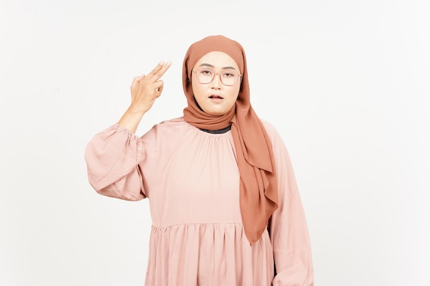 Dedo de arma na cabeça de uma linda mulher asiática usando um hijab isolado no fundo branco