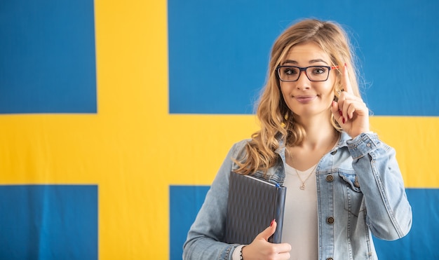 Dedo de aviso levantado por famel loira de óculos em frente à bandeira sueca.