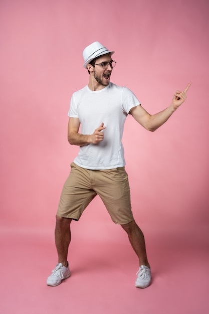 Dedo de braço de jovem sorridente atraente mostrando o espaço vazio em apenas olhar o sinal vestindo casual t-shirt branca isolada.