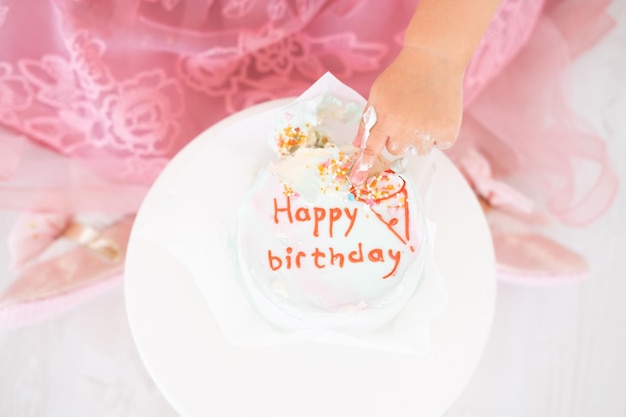 Dedo de criança no bolo de aniversário comemorar primeiro aniversário