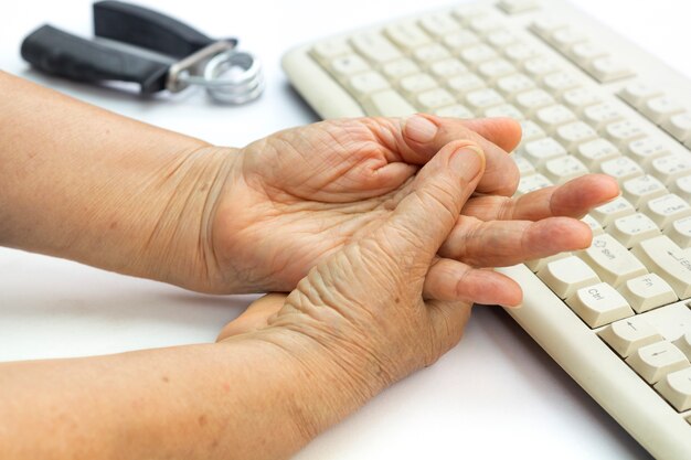 Dedo dolorido de mulher idosa devido ao uso prolongado de teclado e mouse.