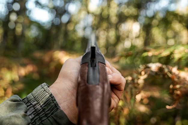 Dedo en el gatillo de un rifle de caza en el bosque de otoño