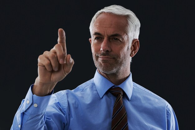 El dedo del hombre de negocios y la interfaz digital para la elección aislados en un fondo de estudio negro Tocar profesional y gesto de la mano en la pantalla hacer clic en el botón y la innovación futura de la tecnología para el CEO senior