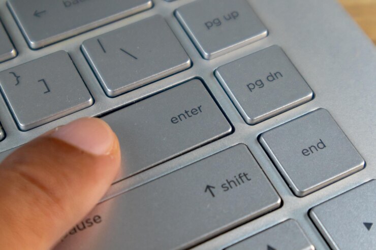 Foto dedo índice presionando el botón de entrada en el teclado del portátil