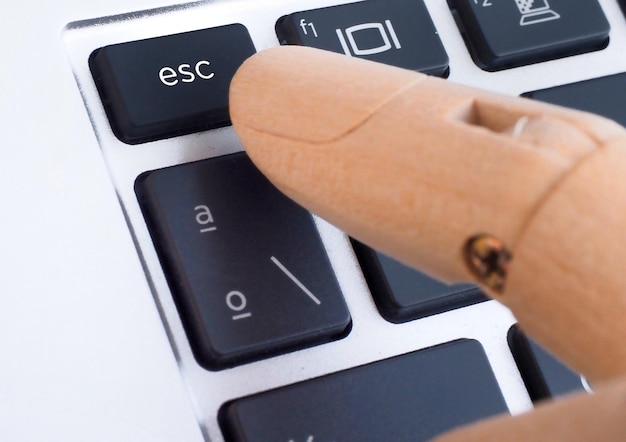 Foto el dedo de madera presionando el botón esc en el teclado de la computadora