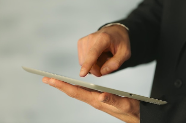 Dedo masculino tocando la pantalla de la tableta en el fondo borroso