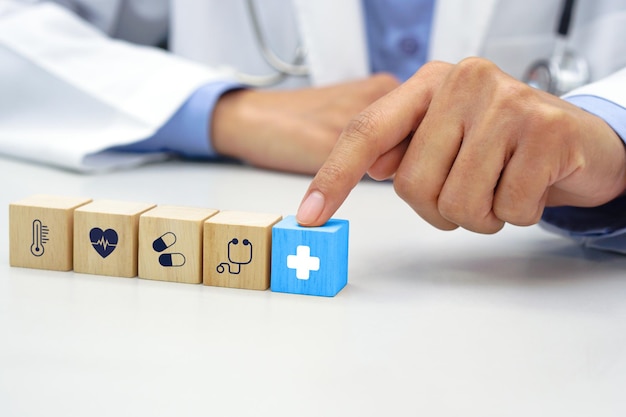 Foto dedo del médico tocando el cubo de bloque de madera azul con símbolo de icono médico sanitario