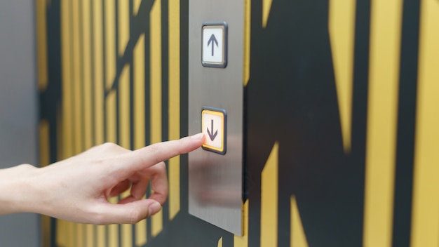 Dedo de mujer presionando un botón hacia abajo del elevador
