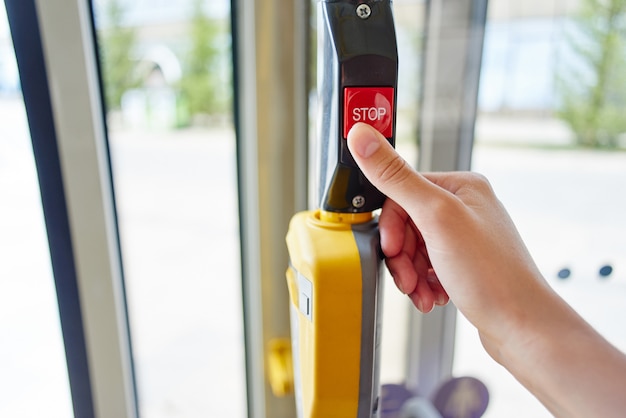 Dedo presiona el botón de parada en la cabina del autobús