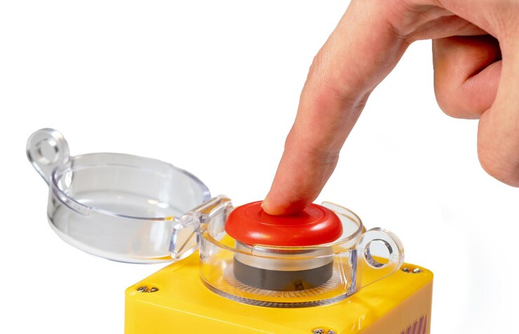 Foto dedo presionando hacia abajo en un gran botón amarillo rojo con una tapa de plástico transparente aislada en fondo blanco