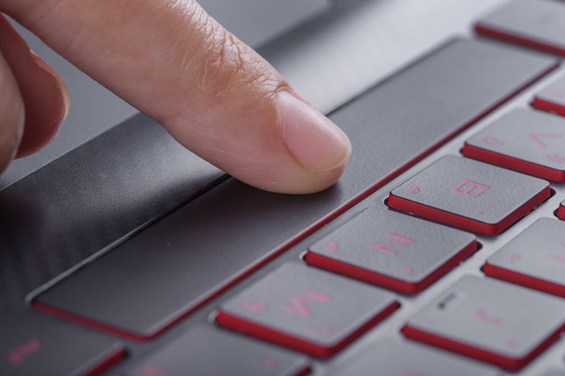 dedo presionando la barra espaciadora en el teclado de la computadora portátil