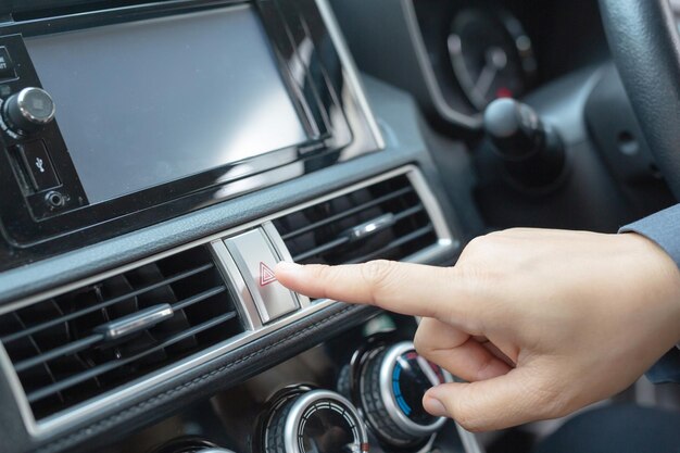 Foto dedo pressione o botão de luz de emergência no carro no painel do carro