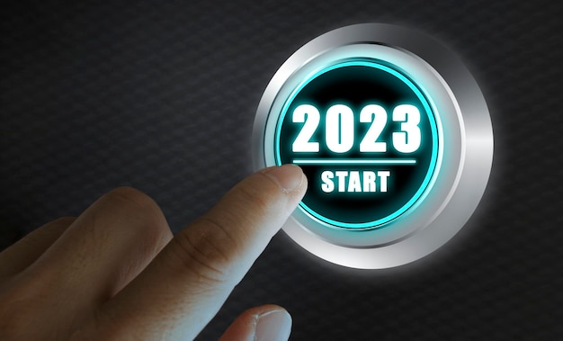 Foto dedo a punto de presionar el botón de encendido de un automóvil con el texto 2023 inicio año dos mil veintitrés concepto