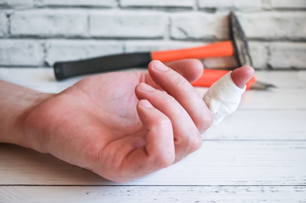 Dedo vendado en la mano del maestro. Un accidente de trabajo: vendar el dedo lesionado del hombre.