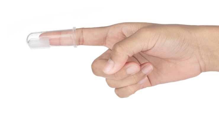 Foto dedos con cepillo de silicona para limpiar los dientes de los bebés aislado sobre fondo blanco.