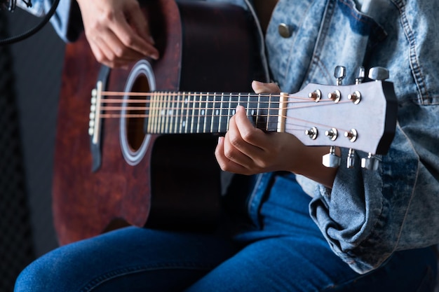 Dedos de mulher closeup segurando mediador com uma guitarra gravando uma música em estúdio de gravação
