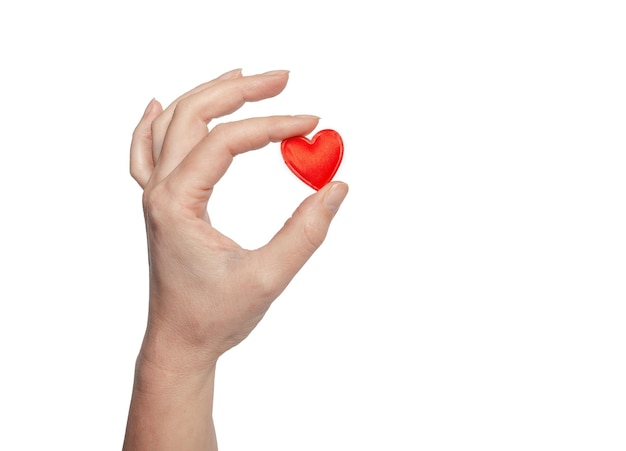 Los dedos femeninos sostienen un pequeño corazón rojo Símbolo de amor